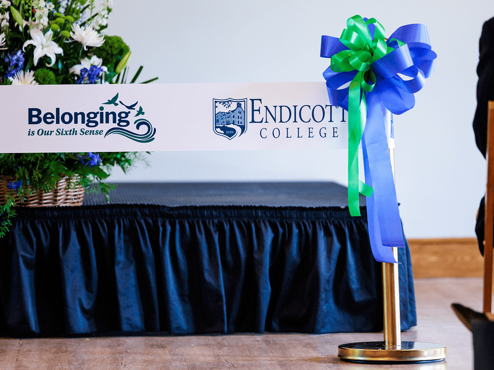A ceremonial ribbon with the Endicott College logo and a "Belonging" slogan, ready for cutting.