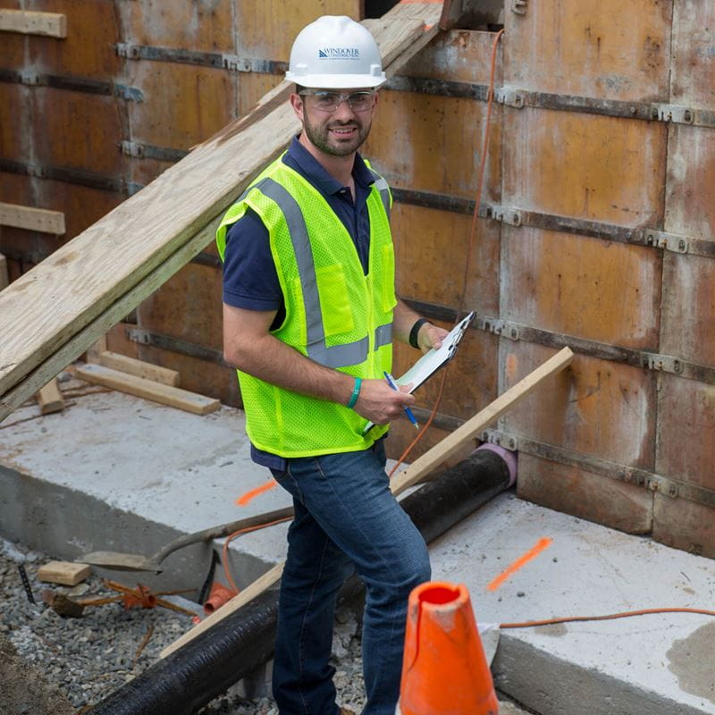 male student/intern working on construction sight with hard hat and yellow vest