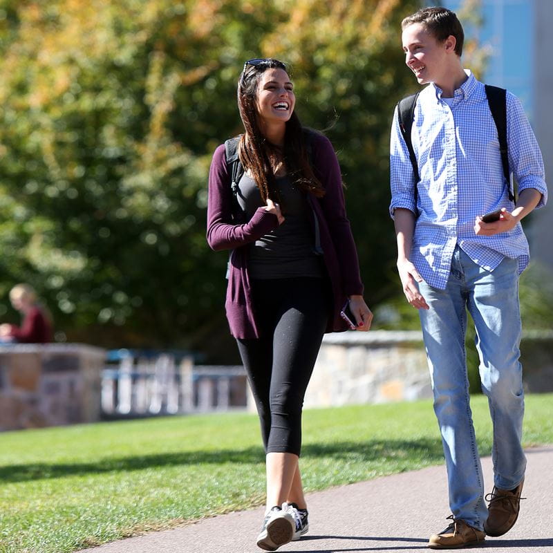 two student walking and talking on sidewalk