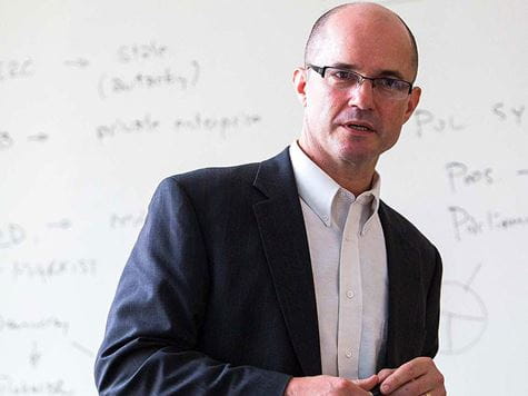 a professor standing in front of his notes on the whiteboard