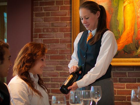 hospitality student offering wine to customer at la chanterelle restaurant at misselwood