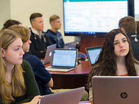 students working in groups on laptops in class