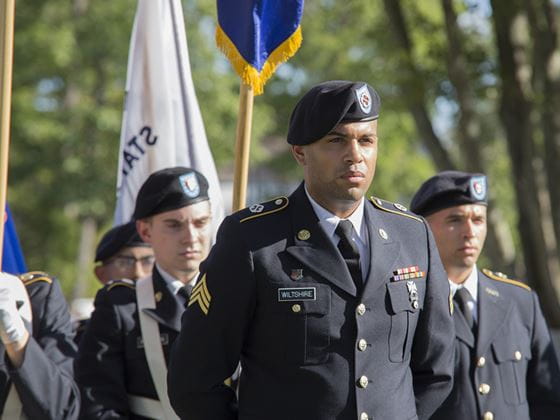 men in armed services dressed in uniform holding flags