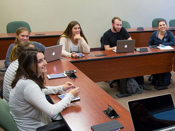 students working on laptops and taking notes in classroom