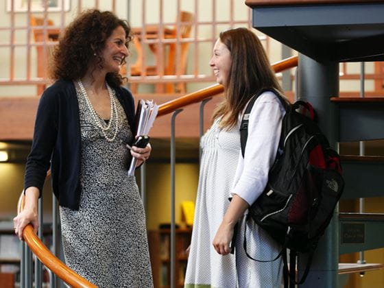 student speaking to professor on steps inside library