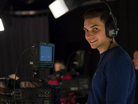 a smiling communications student with headphones on