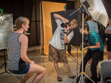 two guys taking pictures of a model with their cameras in a photoshoot