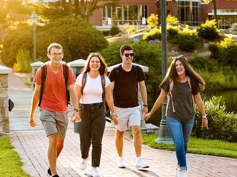 four students walk across a bridge 