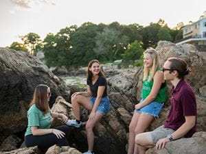 four students talk on the beach