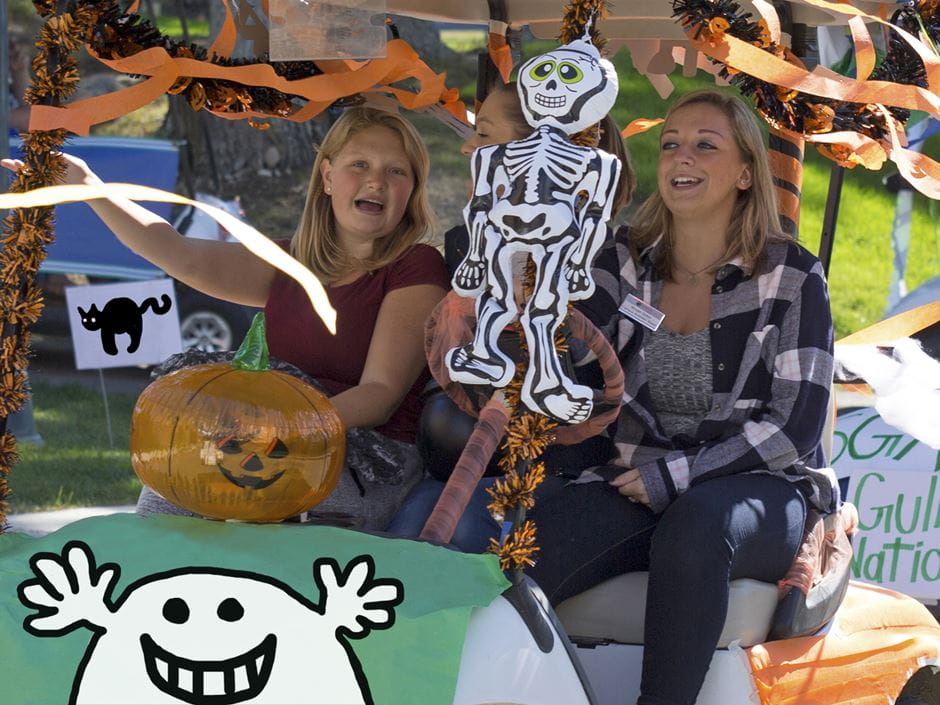 two women riding in a Halloween-themed golf cart