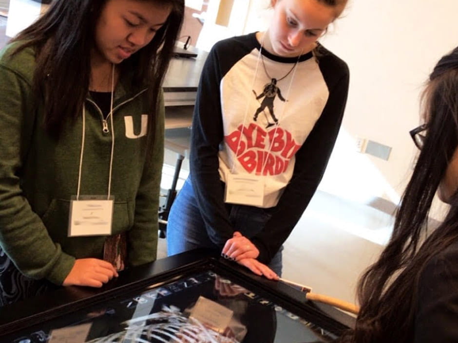 a few girls standing around a skeleton on display