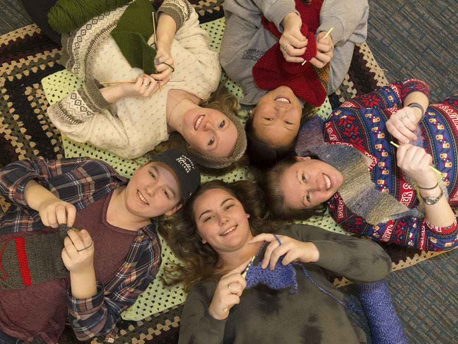 Kennedy Glidden, Lindsay Laflamme, Anna McAlister, Caili Inman, and Ashley Palmer of the Charity Craft Club pose for a group shot while knitting. 