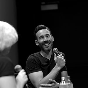 Black and white photo of Matt Leslie '02 speaking into a microphone
