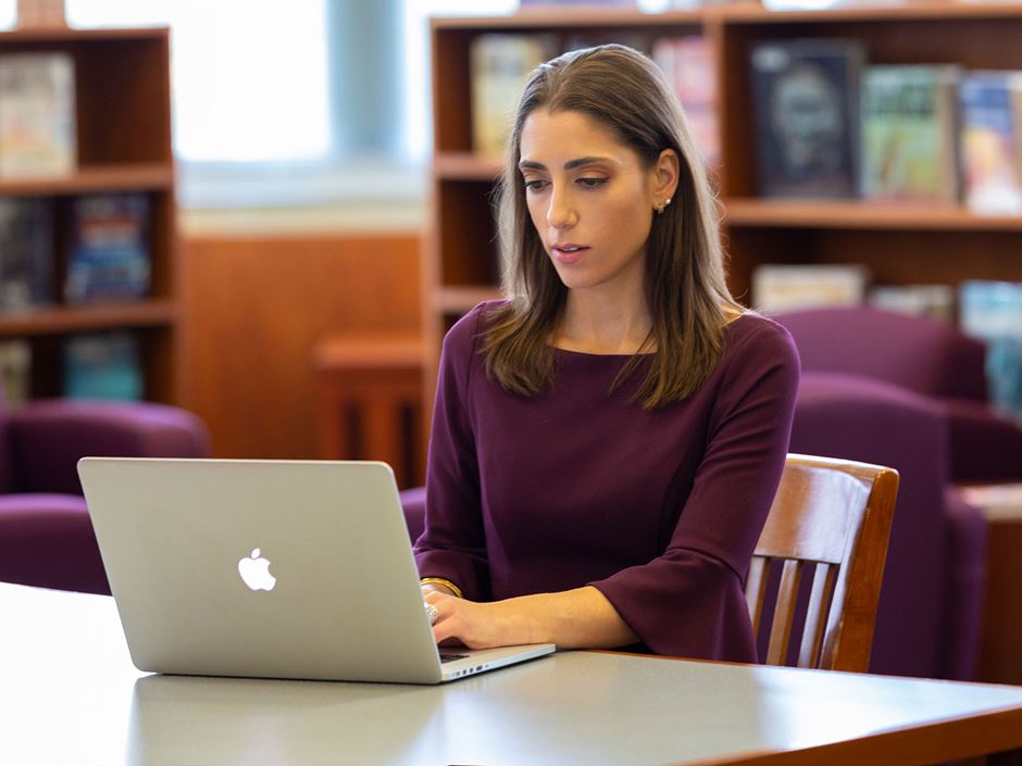 Lara Salahi typing on a laptop in the library 