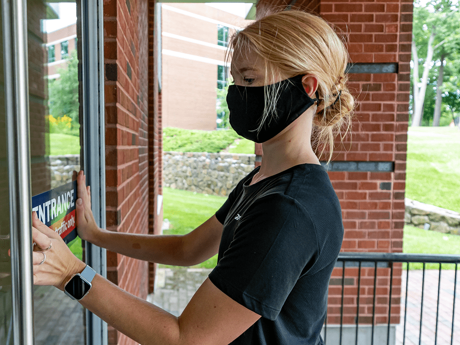 student puts up entrance sticker on door for COVID19 distance measures