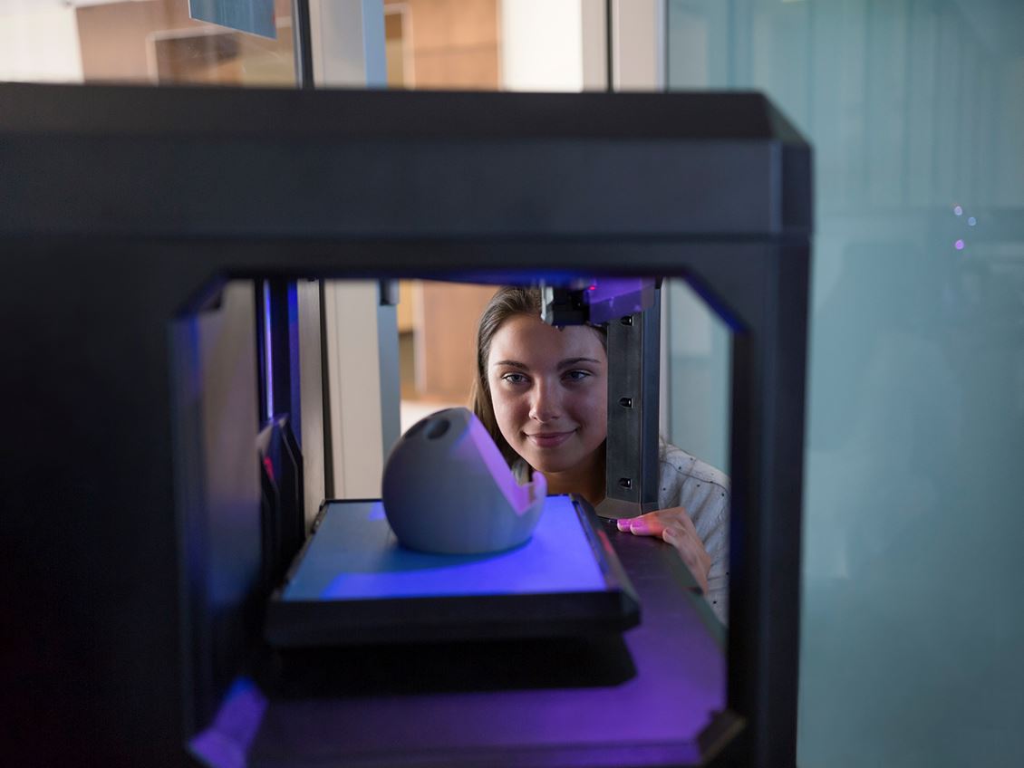 Student looking at a 3D printer