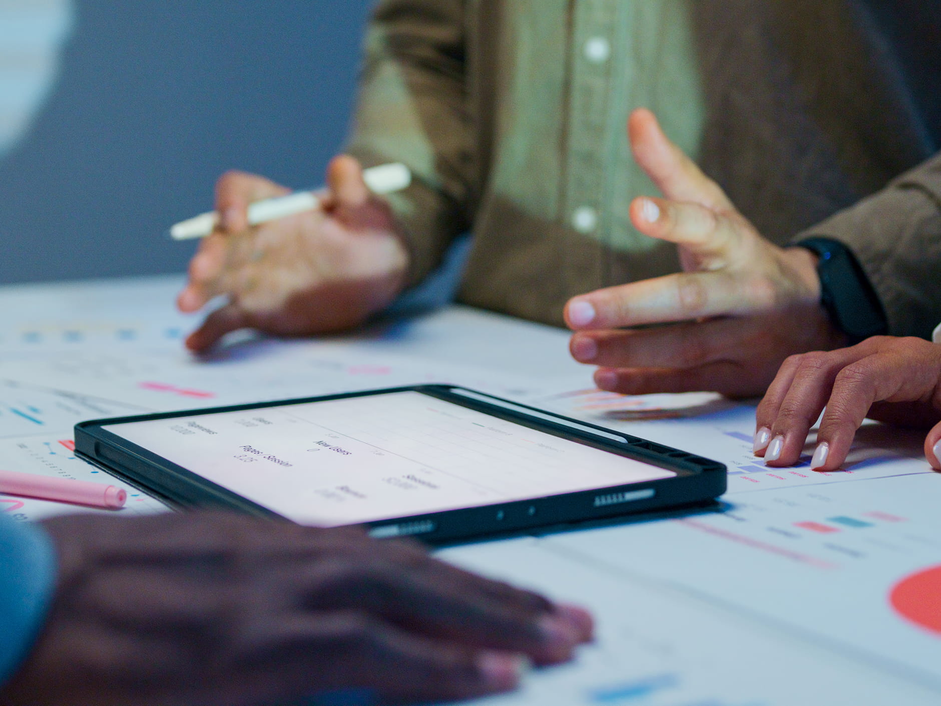 A close-up view of several people collaborating around a table with the focus is on their hands