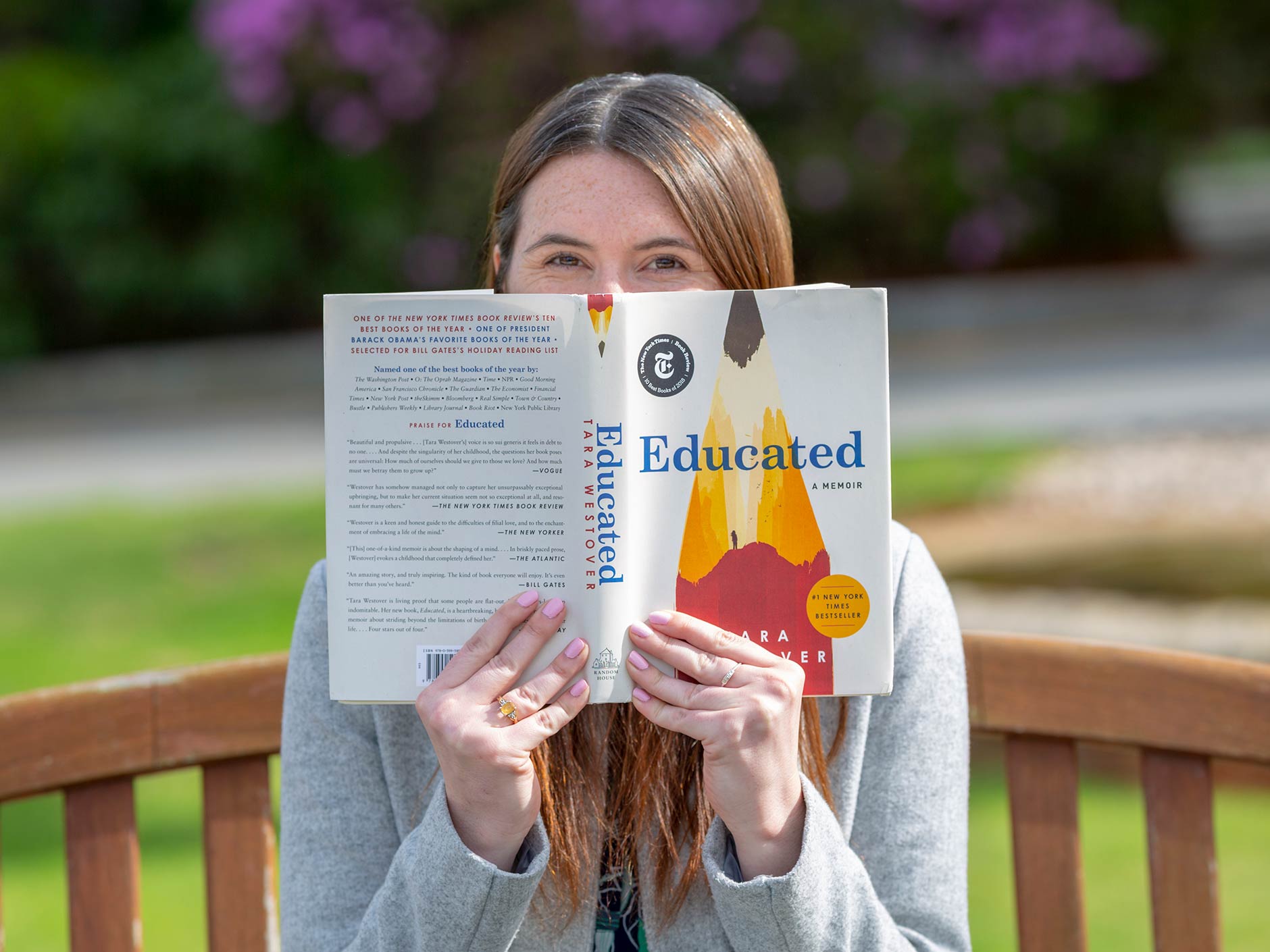 Alumni Diretor Tory Pilbin sitting on a bench outside of College Hall reading a book