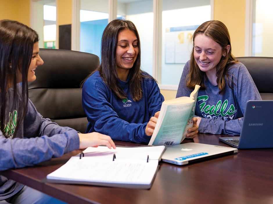 three girls looking at notes on table