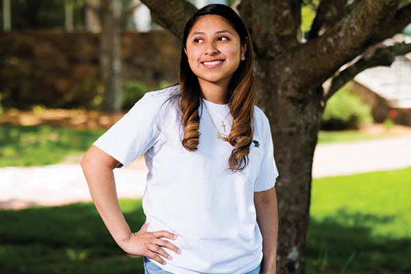 Student standing by tree