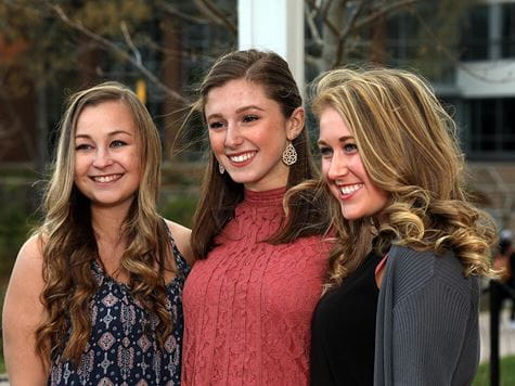 three students smiling/enjoying on campus event