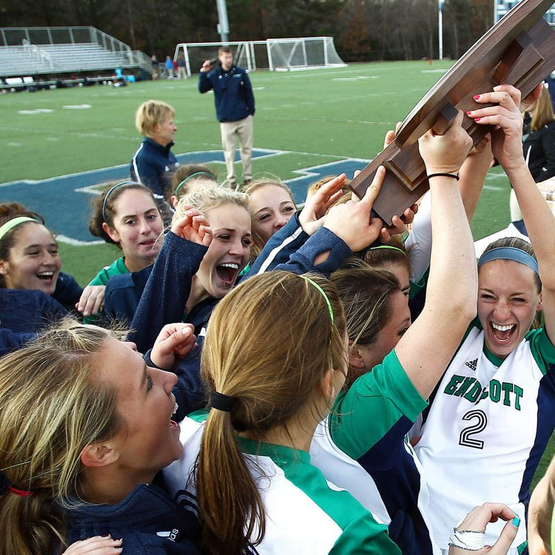 athletic team holding up championship trophy and celebrating victory