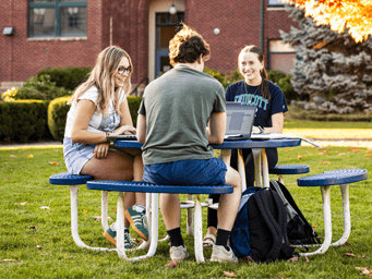 Students sitting at a bench on campus