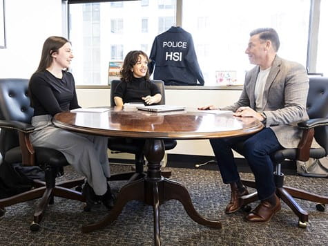 Two female students sitting at a round conference table discussing career plans with a professional male advisor.