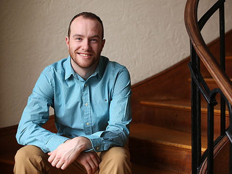 a man smiling and sitting on the stairs with his arms crossed