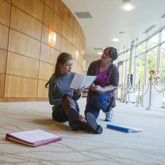 a woman helping a student with her papers