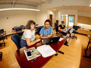 Faculty working with student nurse in scrubs